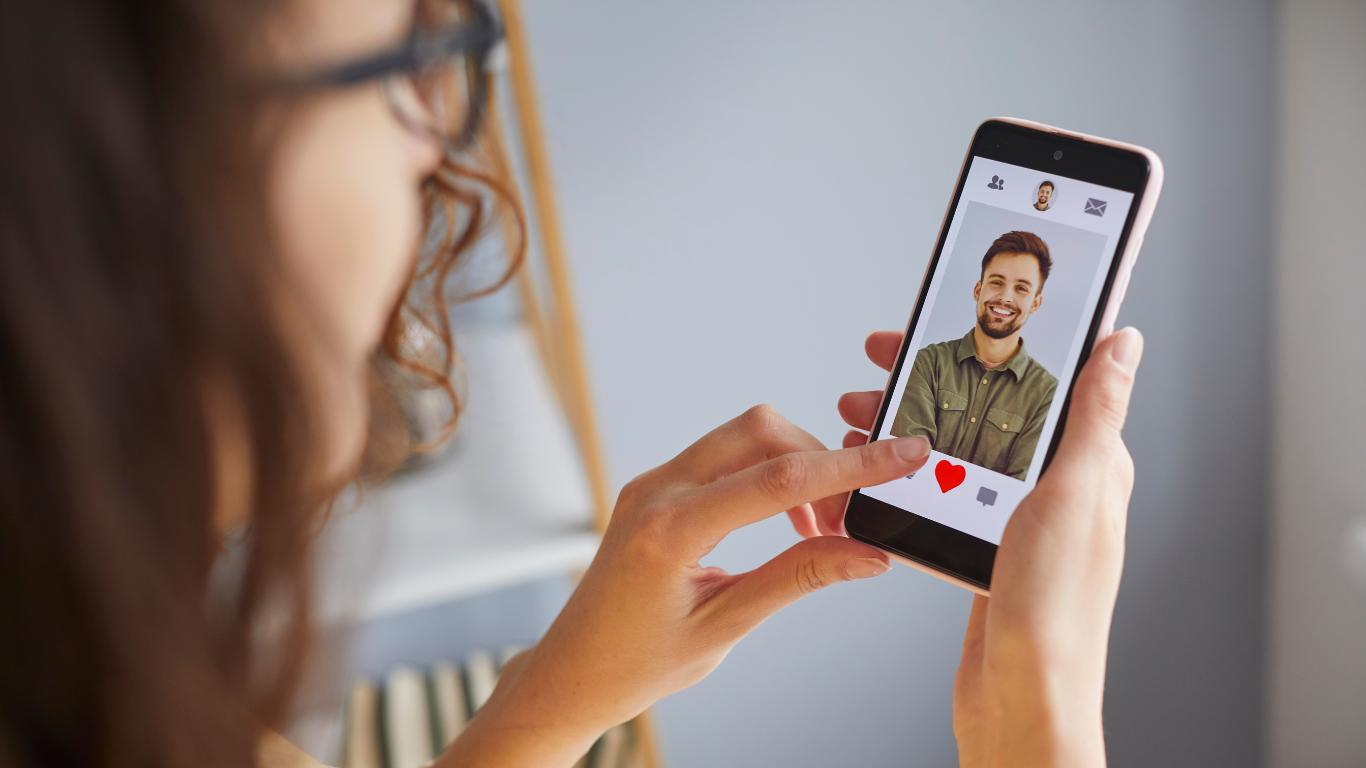 A woman using a dating app on her smartphone, focused on finding potential matches.