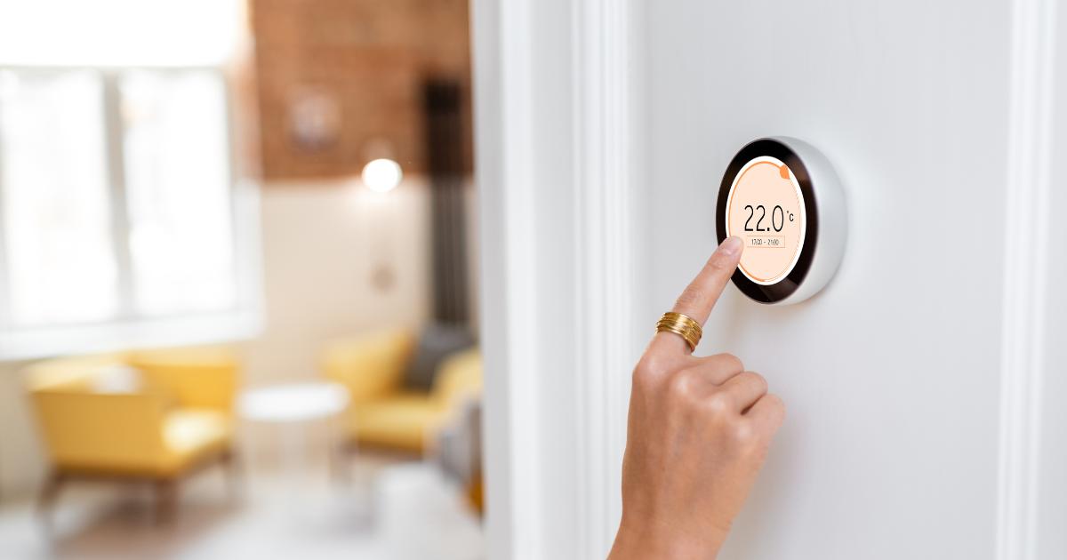 Close-up of a hand adjusting the settings on a digital thermostat, focusing on the display to reduce home energy.