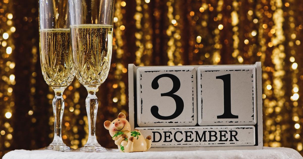 Image of December 31 marked on a calendar, accompanied by two champagne flutes and a gold sparkly background.