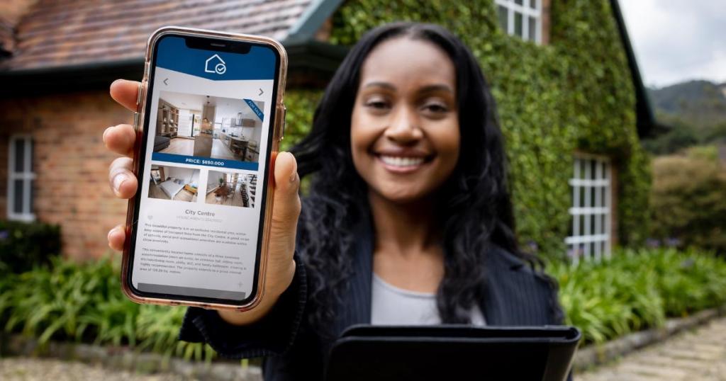 A woman real estate agent holding up her phone, showcasing information related to buying a home.