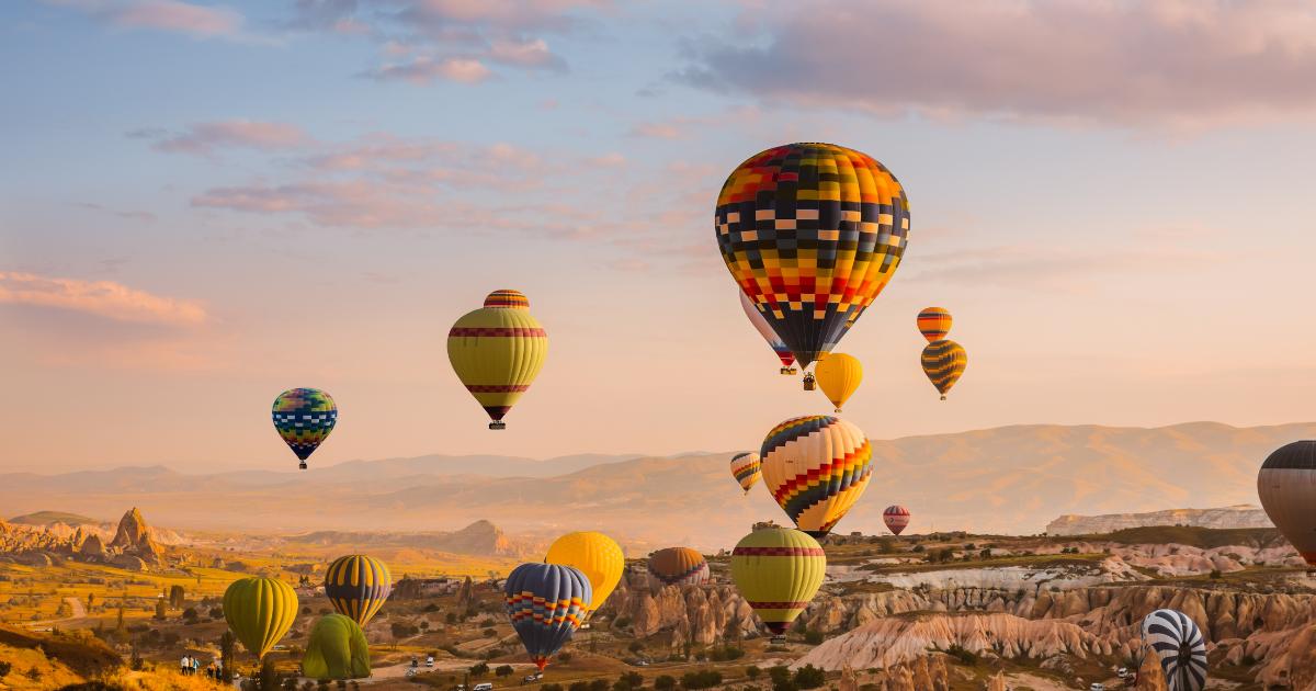 A breathtaking view of Cappadocia, Turkey, with colorful hot air balloons soaring over unique rock formations and scenic valleys, perfect for Instagram travel.