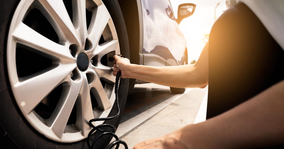 A person checking the tire pressure of a vehicle using a pressure gauge during a car inspection.