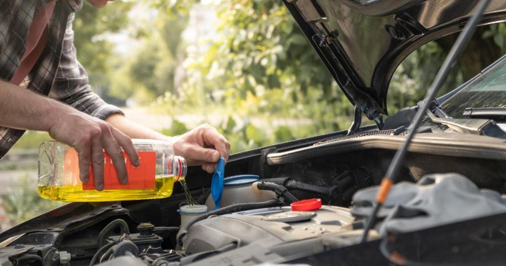 Close-up of a man's hands carefully pouring oil into a car engine.