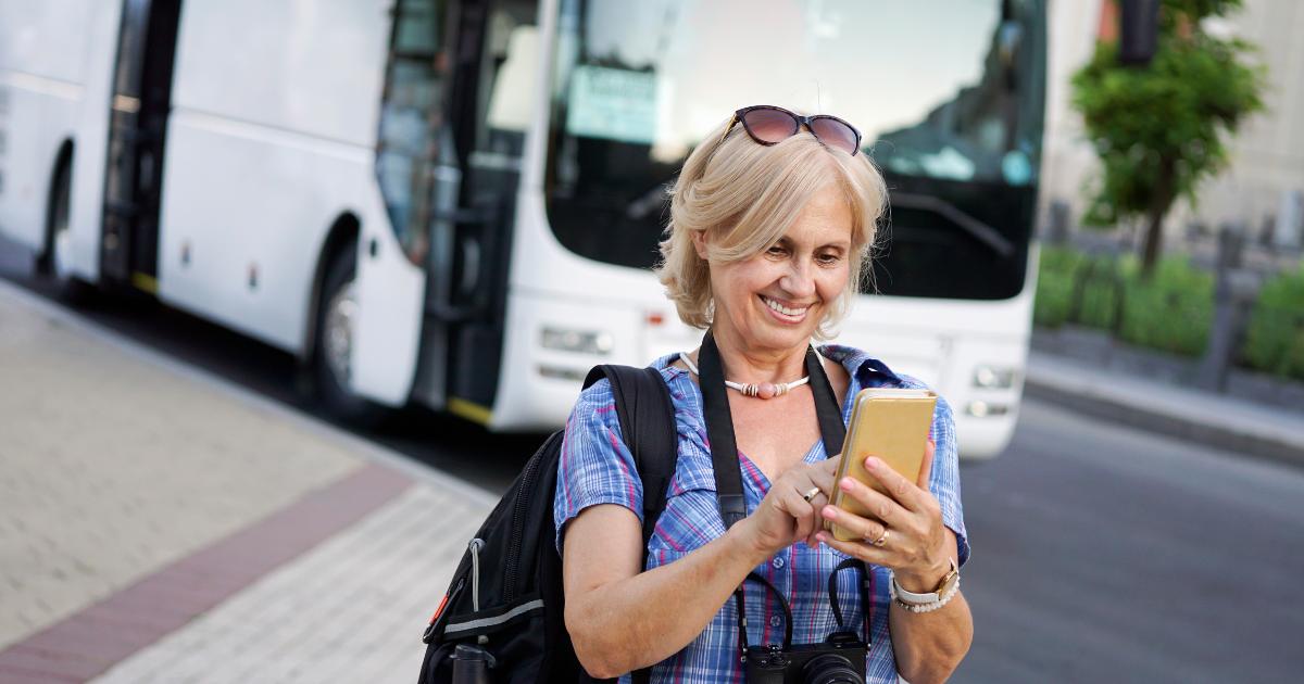 A solo travel female traveler sitting outdoors, looking at her phone for navigation or travel tips.